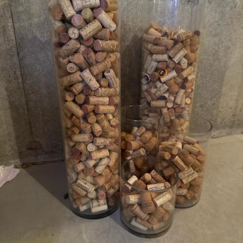 Six glass cylinders full of wine corks. Cylinders vary in size