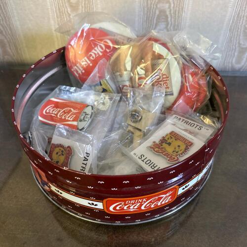Assortment of Vintage Coca-Cola Collectible Pins in a Decorative Tin